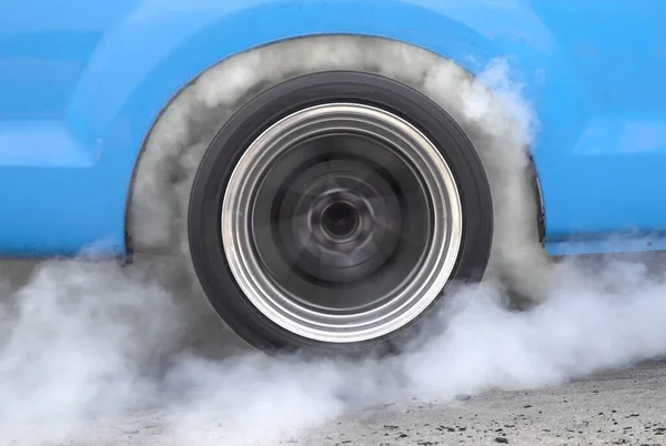 Drag racing car burning tire at starting line in race track