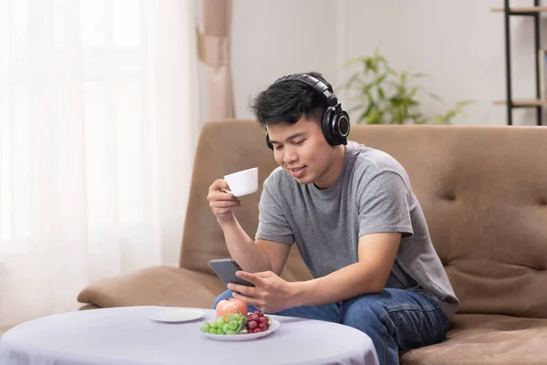 Glücklicher Asiatischer Kerl Sitzt Entspannt Auf Dem Sofa Hört Und — Stockfoto