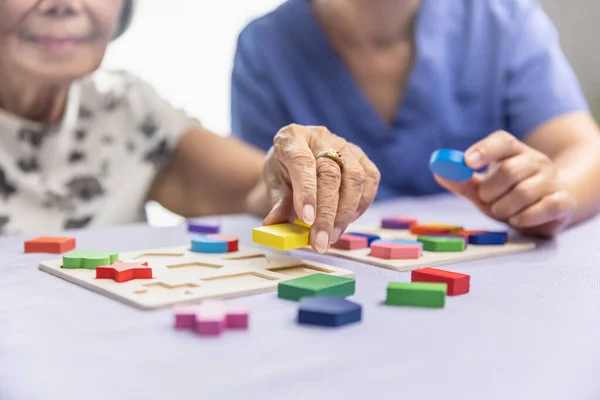 照顾者和老年妇女玩木制字谜游戏预防痴呆症 — 图库照片