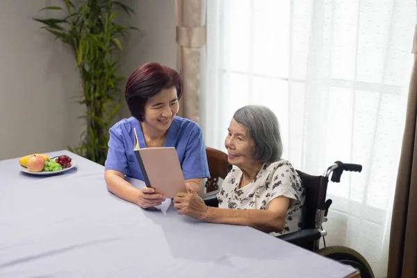 Oudere Vrouw Die Een Boek Voorleest Voor Dementietherapie Met Verzorger — Stockfoto