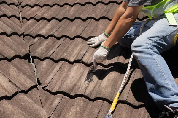 古いタイル屋根の亀裂を修正するために防水屋根コーティング修復を使用して労働者の男 — ストック写真