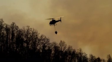 Yangın söndürme helikopteri yangına su bırakıyor.