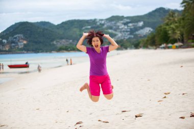 Happy middle aged tourist jumping at chaweng beach in koh samui ,Thailand. clipart