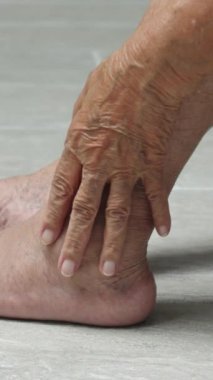 Yaşlı kadın masajı varisli damar ve şişmiş ayak. Dikey video.