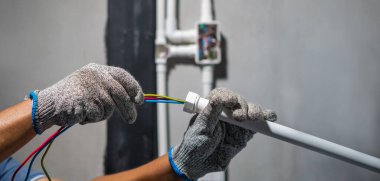 Elektrikçi güneş çevirici sisteminden PVC kanalı üzerinden kablo çekiyor.