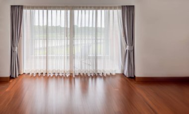Boş oturma odasının içi. Büyük parlak penceresi ve boş odasında beyaz perdeleri var.