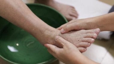 Sıcak suyu içmeden önce yaşlı kadın ayak masajı yapıyor..