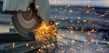 İnşaat alanında çelik dikdörtgen boru kesen işçiler.