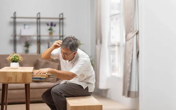 stock image Asian older man finding something that he forgot it in drawers.