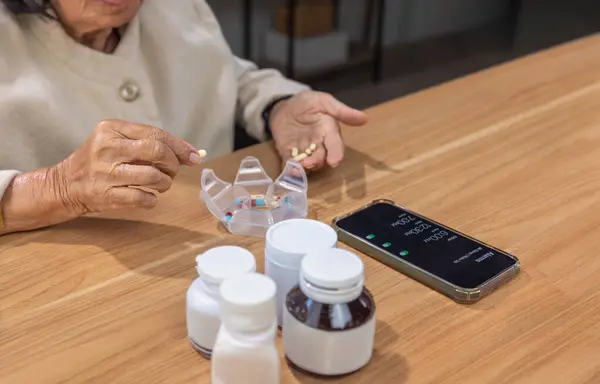 stock image Elderly woman putting pills into pill box for the week.