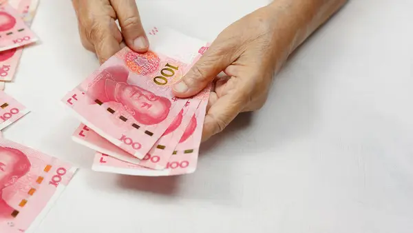 stock image Hand Holding Stack of 100 Yuan Notes on table.  Translate alphabet Yibai yuan meaning one hundred yuan.