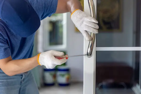 stock image Worker install handle on aluminium swing door.