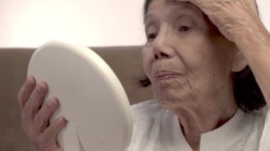 Yaşlı bir kadın huzurevinde yüz kırışıklıklarına ayna tutuyor..