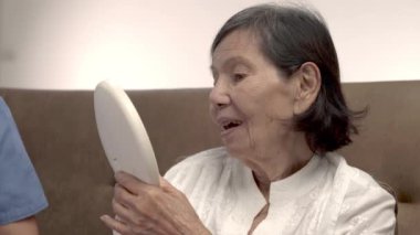 Yaşlı bir kadın huzurevinde yüz kırışıklıklarına ayna tutuyor..