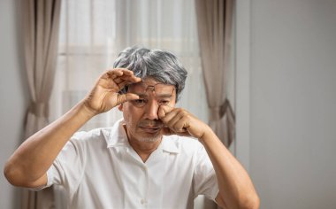 Senior asian man has eyestrain and fatigue.