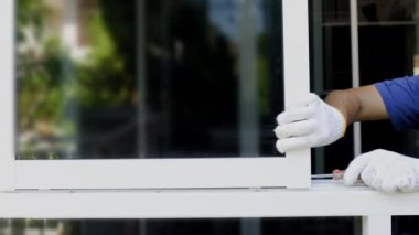 Tamirci sürgülü pencereyi tamir ediyor. Bir tekerlek ayarla ve kancayı kilitle..