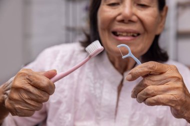 Dişlerini diş ipiyle fırçalayan yaşlı Asyalı kadın..