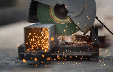 İnşaat alanında çelik dikdörtgen boru kesen işçiler.