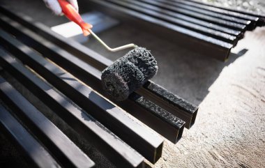 Worker painting steel post in construction site.