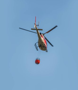 Yangın söndürme helikopteri orman yangınını söndürmek için su taşıyor..