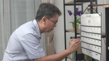 Kafası Karışık Asyalı Bunak Adam Duvar Takvimine Bakıyor.
