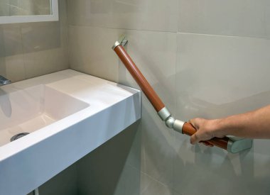 Yaşlı kadın banyoda güvenlik için tırabzanları tutuyor.