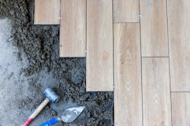 İşçi, yer kiremitlerinin doğru hizalaması için plastik fayans boşlukları kullanır, yarı kuru zemin perdeli.