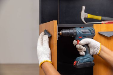 Tamirci mutfakta dolap kapısını tamir ediyor.