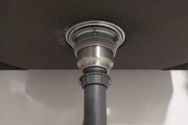 Tesisatçı lavabonun altındaki tıkanıklığı tamir ediyor..