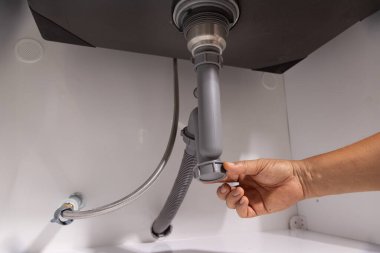 Lavabonun altındaki tıkanıklığı tamir etmek için su tesisatı açık..