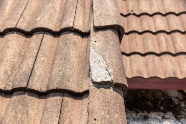 Tamire ihtiyacı olan hasarlı eski çatı kiremiti.