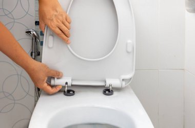 İşçi menteşe lastik tıpası ve Klozet Koltuğu vidalarını değiştirir