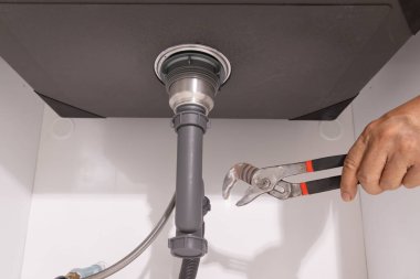 Lavabonun altındaki tıkanıklığı tamir etmek için su tesisatı açık..