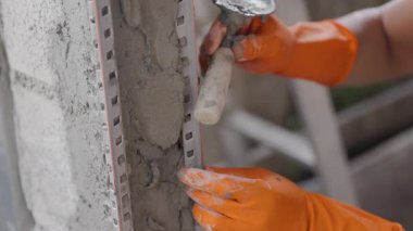 Bir pencere köşesini kaplamak için pvc köşe boncuğu kullanan inşaat işçisi.