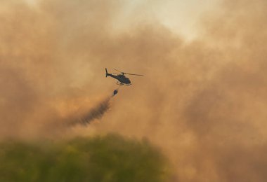 İtfaiye helikopteri orman yangınını söndürmek için Watthar kovası taşıyor..