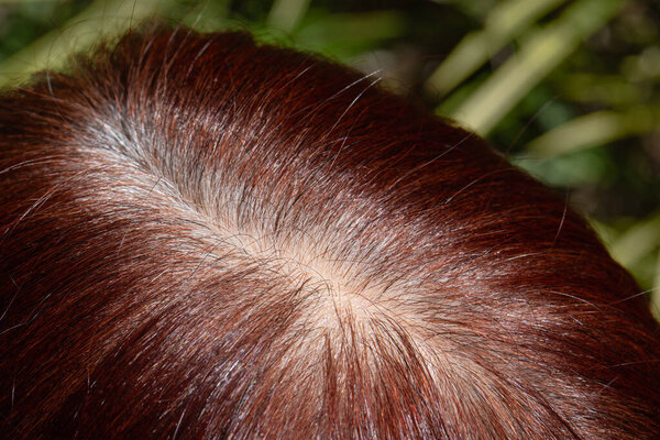 Senior aged asian woman concern about gray hair in menopause.