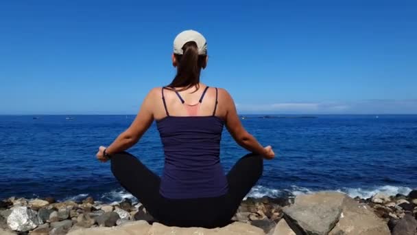 Young Relaxed Woman Meditating Sitting Boulder Ocean Coast — Stockvideo