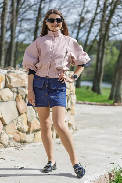 Молодая Женщина Розовой Куртке Джинсовой Юбке Позирует Открытом Воздухе Возле — стоковое фото