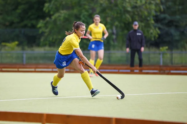 Field hockey female player leading the ball in attack. Young woman playing in field hockey tournament