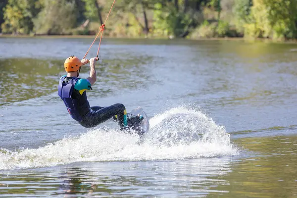 Young man surfing on the pond, is pulled by a cable machine.