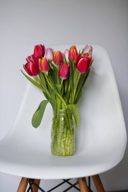 beautiful tulips stand in a vase by the window