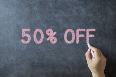 Elinde tebeşir tutan ve metni% 50 indirimle kara tahtaya yazan bir adam. 