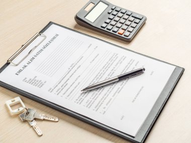 Türkçe emlak alım-satım sözleşmesi, anahtar ve hesap makinesi masada ve elinde kalem tutan bir el