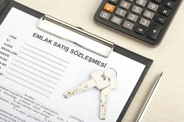 Türkçe, anahtar, hesap makinesi ve kalemle emlak satış anlaşması.