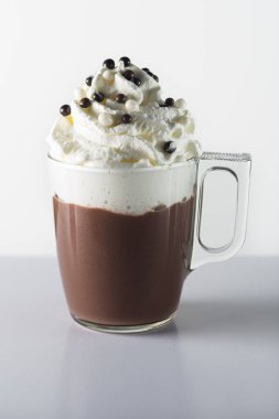 Glass cup with handle containing chocolate, whipped cream and chocolate balls.