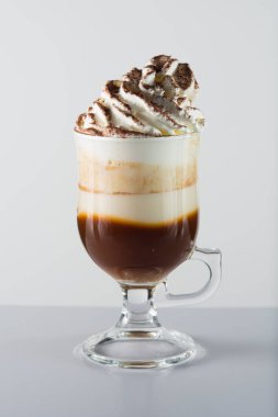 Glass cup with handle containing chocolate, whipped cream and chocolate balls.
