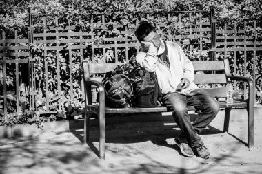 BARCELONA, İspanya - 10 Mayıs 2022: Asyalı bir adam valizinin üzerinde dinleniyor..