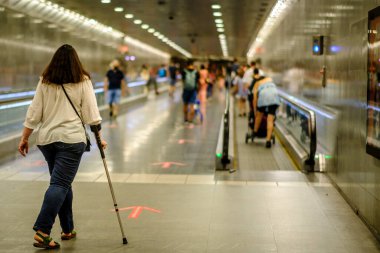 BARCELONA, İspanya - 31 Mayıs 2022: Koltuk değnekli bir kadın şehrin banliyösünde yürüyor.