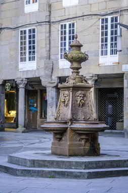PONTEVEDRA, SPAIN - 7 Temmuz 2022: Yüzleri rahatlatılmış bronz çeşme, tipik şehrin tarihi merkezi.