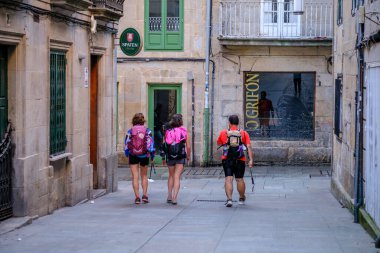 PONTEVEDRA, SPAIN - 7 Temmuz 2022: Camino de Santiago 'ya ait şehir sokaklarından birinde üç hacı yürüyor.